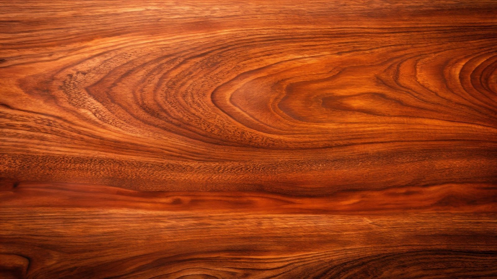 Gros plan d'une surface en bois avec des motifs de grain riches et tourbillonnants dans des tons bruns chauds.
