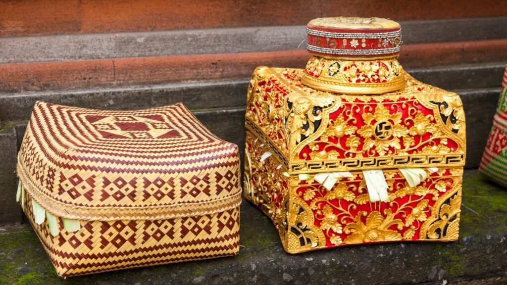 Deux boîtes d'offrandes balinaises au design complexe : l'une tissée et carrée, l'autre ornée de motifs rouges et dorés.