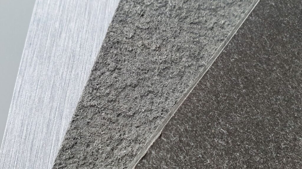 Gros plan de trois surfaces texturées qui se croisent : une surface claire et rugueuse ; un milieu plus foncé et grossier ; et une zone sombre et lisse.