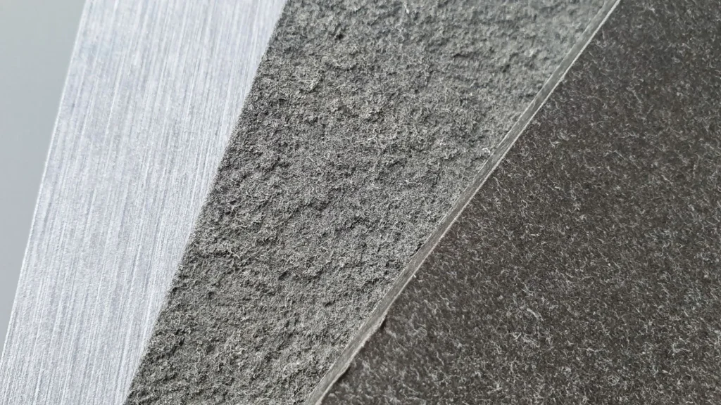 Gros plan de trois surfaces texturées qui se croisent : une surface claire et rugueuse ; un milieu plus foncé et grossier ; et une zone sombre et lisse.