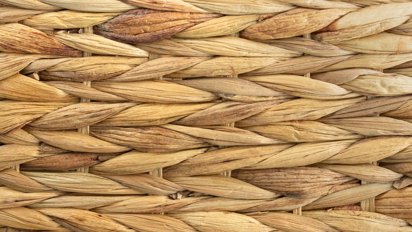 Gros plan de fibres naturelles tissées selon un motif à chevrons, avec différentes nuances de beige et de brun.