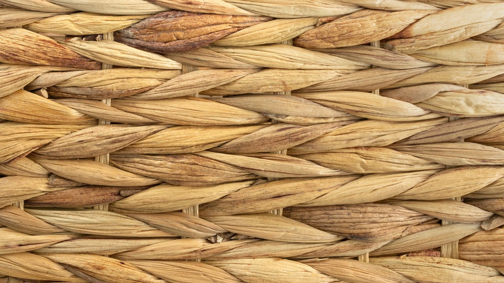 Gros plan de fibres naturelles tissées selon un motif à chevrons, avec différentes nuances de beige et de brun.