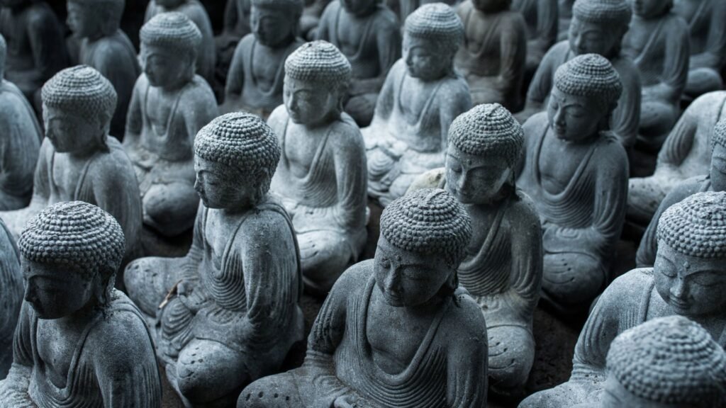 Rangées de petites statues de Bouddha en pierre dans des poses méditatives, avec des détails complexes sur les robes et les cheveux.