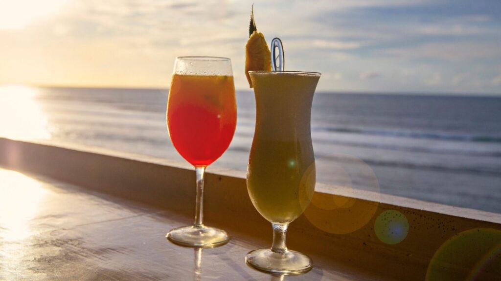 Deux cocktails avec vue sur le coucher de soleil sur la plage en arrière-plan.