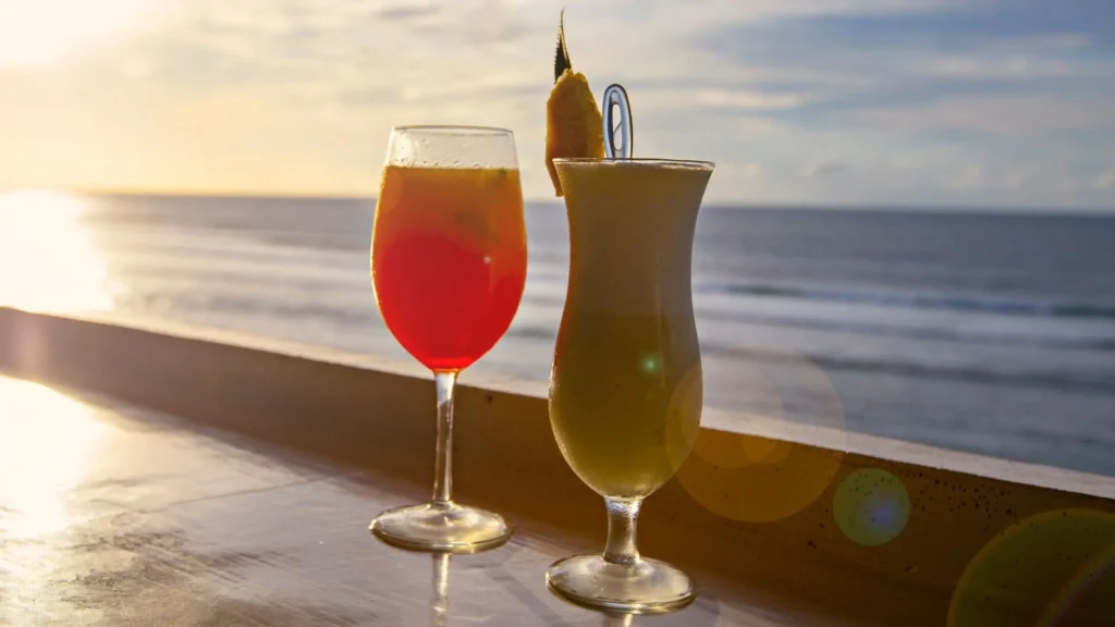 Deux cocktails avec vue sur le coucher de soleil sur la plage en arrière-plan.