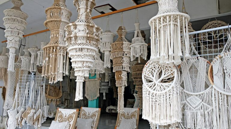 Décoration en macramé suspendue dans une boutique, présentant divers motifs et dessins complexes dans des tons neutres.